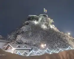 Krušnica, snježna tvrđava na brdu s osvjetljenjem i zastavama, noću. Krušnica tvrđava pod snježnim pokrivačem noću s osvjetljenjem.