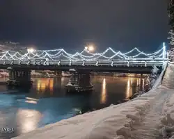 Most u Mostaru osvetljen zimskom atmosferom i refleksijama na vodi. Mostar most u zimskom okruženju sa osvetljenim lampama.
