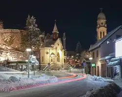 Noćni prizor u Krušnici s osvetljenom crkvom i snježnim ulicama, mirna zimska scena. Zimski pejzaž u Krušnici s osvetljenom crkvom i snježnim ulicama.
