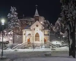 Crkva u Krušnici okružena snježnim drvećem i osvjetljenjem noću, slikoviti prizor zimskog pejzaža. Crkva u snijegu s osvjetljenjem noću u Krušnici.