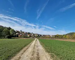 Krušnica rijeka okružena zelenim poljima i selom pod plavim nebom.
