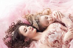 Mother and daughter laughing in princess costumes. Studio portrait of mother with daughter in pink princess dresses – children’s photography NYC