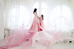 Mother and daughter posing as princesses in the studio. Studio portrait of mother with daughter in pink princess dresses – children’s photography NYC