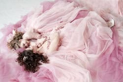 Mother holding her daughter in a playful princess pose. Studio portrait of mother with daughter in pink princess dresses – children’s photography NYC