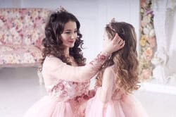 Close-up of mother and daughter smiling in princess gowns. Studio portrait of mother with daughter in pink princess dresses – children’s photography NYC