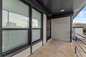Spacious apartment balcony with city views, metal railing, and sleek black accents.