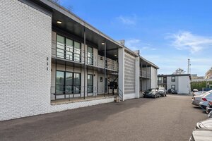 Contemporary urban apartment building exterior with parking lot and modern design.