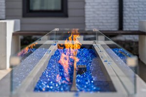 Luxury outdoor fire feature with blue glass stones and bright flames, perfect for patio decor.