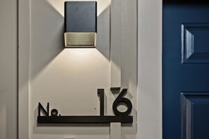 Contemporary house number plate with light fixture, mounted on a wall, highlighting home address.