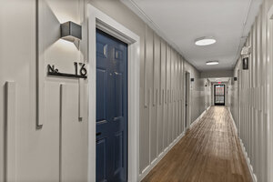 Bright, clean apartment corridor featuring a blue front door and contemporary lighting.