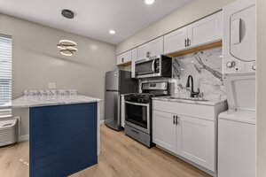 Bright, contemporary kitchen featuring stainless steel appliances and elegant marble backsplash.