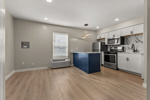 Bright, stylish kitchen featuring stainless steel appliances, white cabinetry, and a blue island.