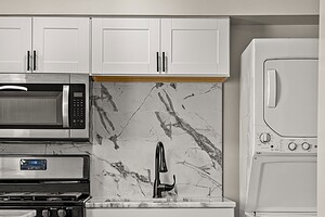 Clean white kitchen with black sink and modern appliances.
