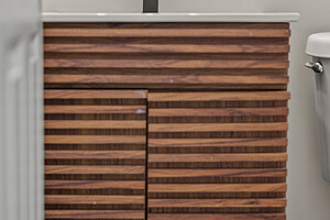 Bathroom vanity with wood slats, black faucet, and round mirror.