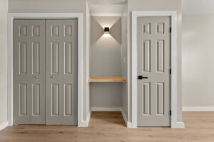 Closet design showing gray bi-fold doors and a small shelf with contemporary lighting.