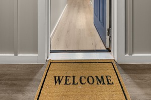 Bright home entrance featuring a blue door, modern hallway, and welcoming "Welcome" mat.