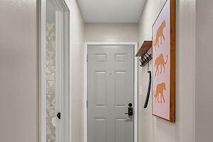 Bright hallway with sleek gray door, playful animal art, and soft lighting, designed for a cozy urban home.