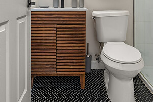 Bright bathroom with sleek wooden vanity, round mirror, and contemporary decor.