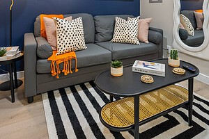 Stylish living room with navy wall, abstract art, gray sofa, patterned pillows, and modern decor.