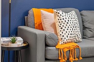 Contemporary living room featuring colorful cushions, a cozy orange throw, and modern lighting.