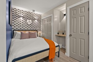 Stylish bedroom featuring patterned wall, soft bedding, and ambient lighting.