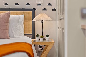 Chic bedroom setup featuring a cozy bed, bedside lamp, and modern wall decor.