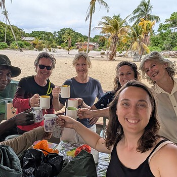 A diverse group of friends toasting with coffee mugs on an outdoor beach patio