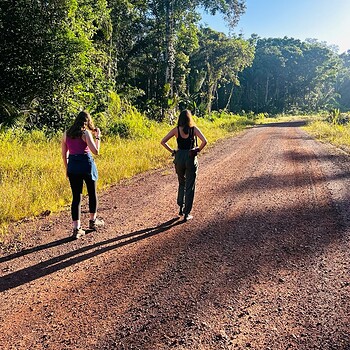 Photo two women walking on dirt road forest 2026 05