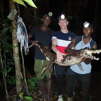 Three men holding crocodile night 2026 05