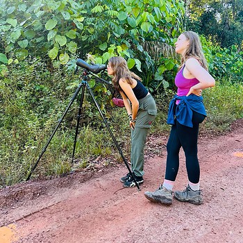 Two women birdwatching spotting scope forest 2026 05
