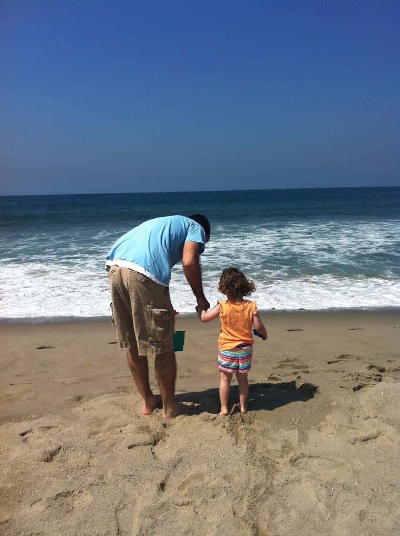 A father and daughter look out at the Pacific Ocean.