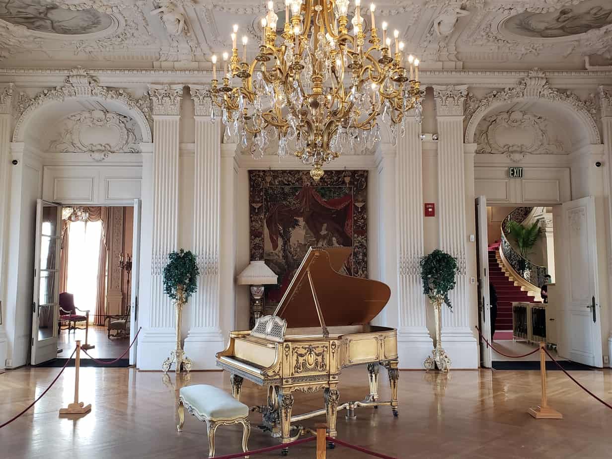 An elegant room with a crystal chandelier and a grand piano