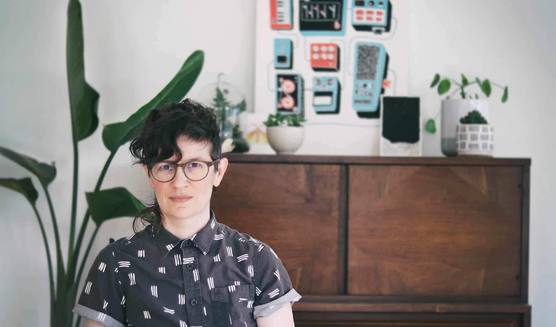 portrait of E seated in front of art and house plants