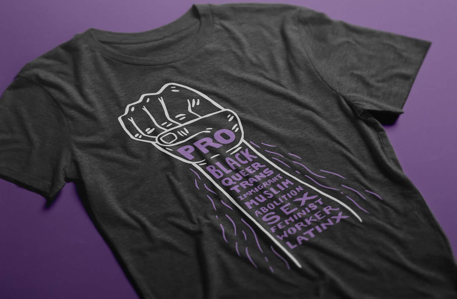 Charcoal heather gray T-shirt with an illustrated line drawing of a fist. The fist and arm contain hand drawn stacked purple type that reads 