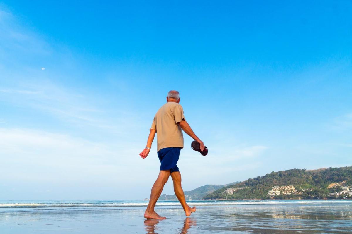 This shows an older man walking on a beach