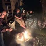 With camping guests around camp fire