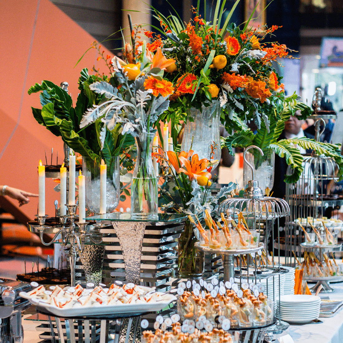Vibrant orange and green floral centerpiece with appetizer displays at Mongkol Catering in Thailand.