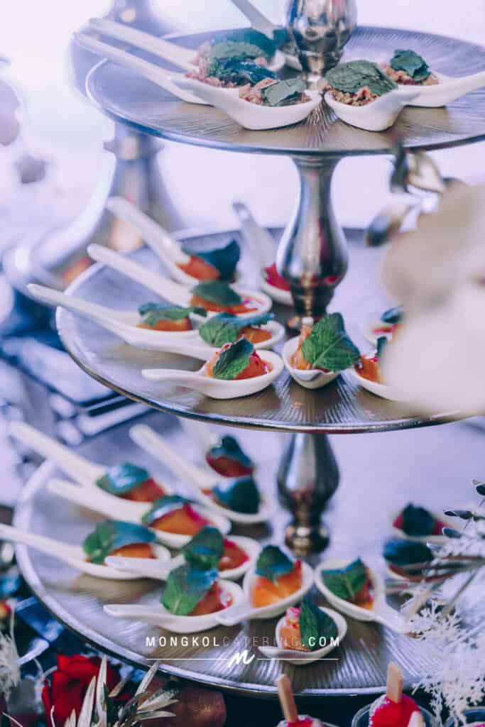 Mini appetizer servings with fresh herbs for events in Thailand placed on a tiered serving tray.