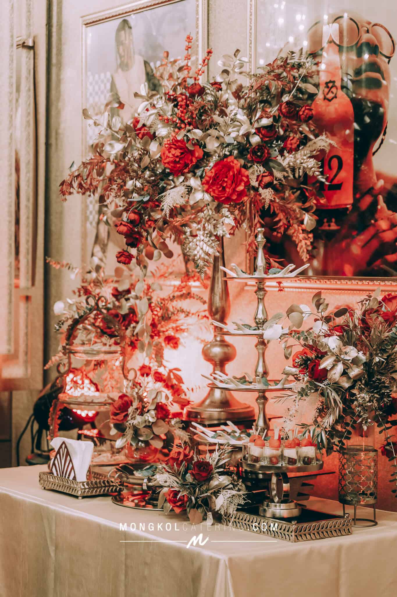 Elegant floral centerpiece with red roses and greenery at Mongkol Catering event in Thailand.