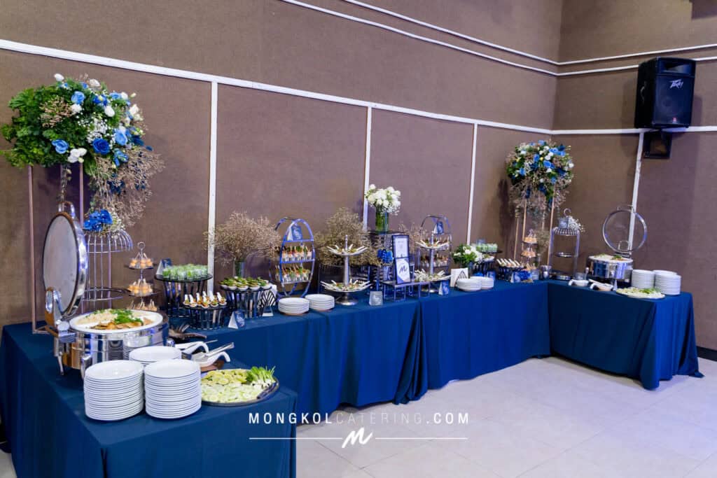 Colorful buffet setup for event catering in Thailand with floral decorations and organized food stations.