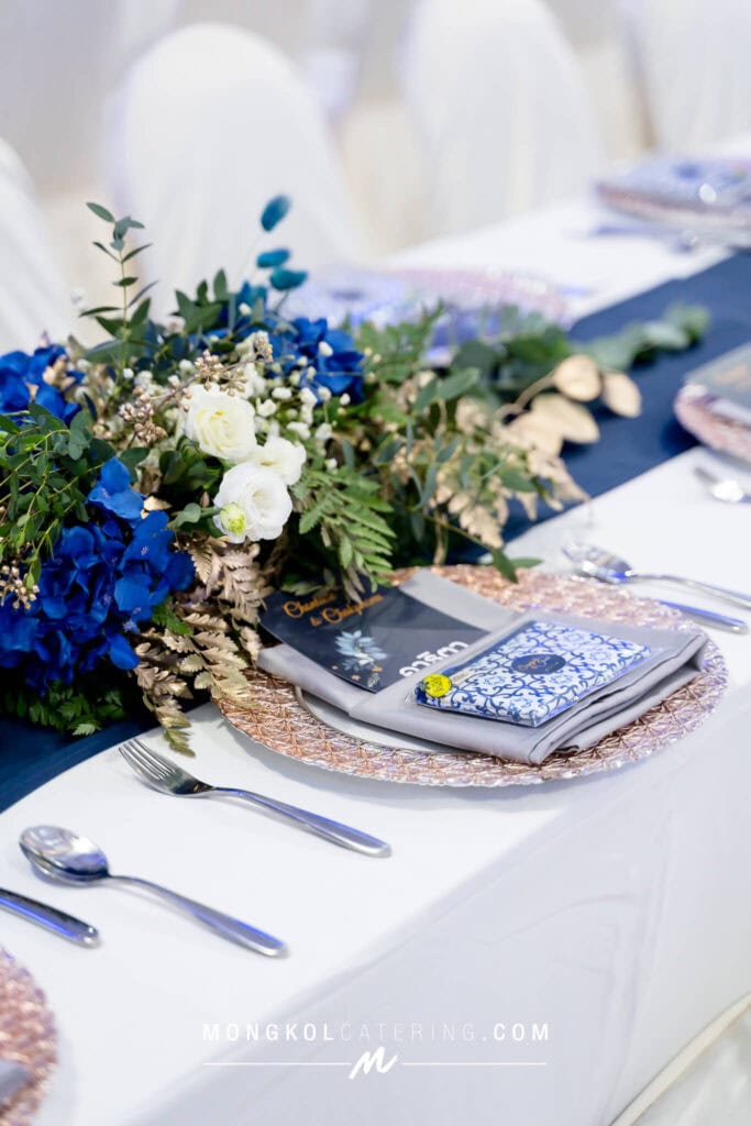 Elegant event table setup with floral centerpiece, fine china, and silverware in Thailand.