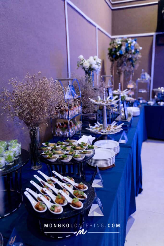 Elegant food display setup with floral decorations for events in Thailand| Mongkol Catering event services.