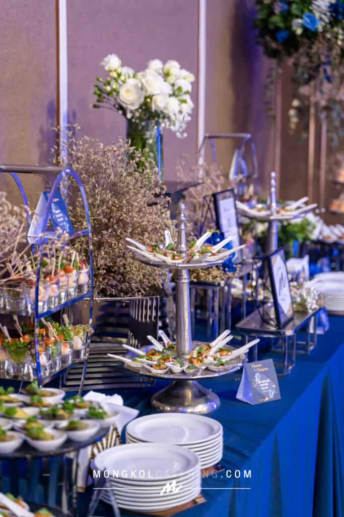 Elegant Thai event catering setup with floral decorations and delicious appetizers.
