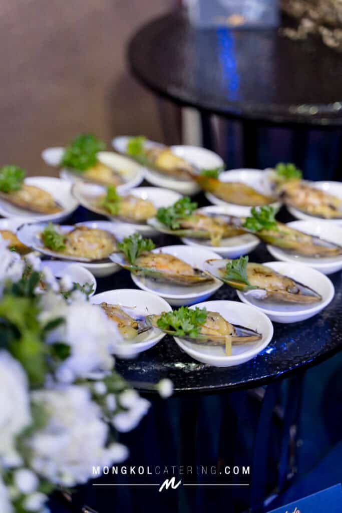 Fresh grilled oysters garnished with herbs, served at Mongkol Catering event in Thailand.
