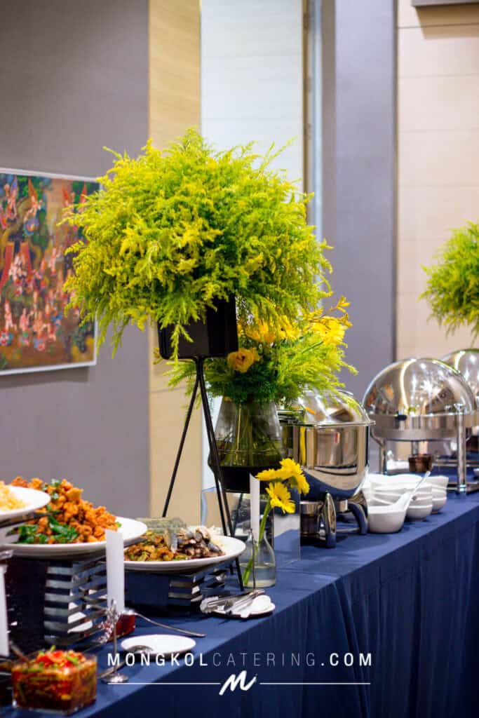 Vibrant yellow floral centerpiece at a catered event in Thailand by Mongkol Catering.