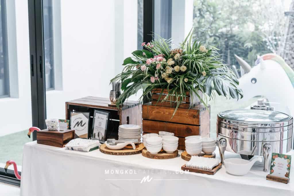Colorful flower arrangement and event catering setup in Thailand with ceramic bowls and a tea warming pot.