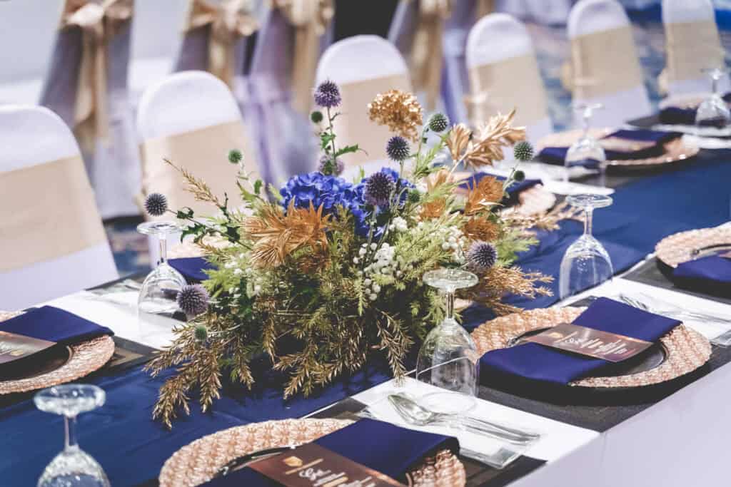 Elegant floral centerpiece at a Thai event table, with navy blue and gold accents.