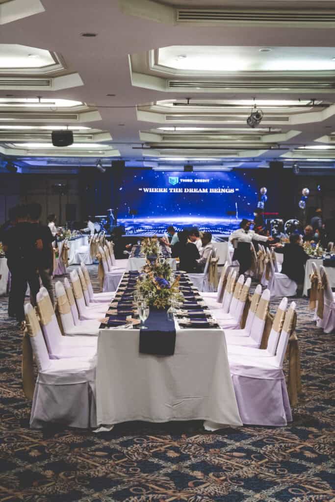 Luxurious banquet setup at a Thai event venue, featuring elegantly decorated tables and a stage with LED display.