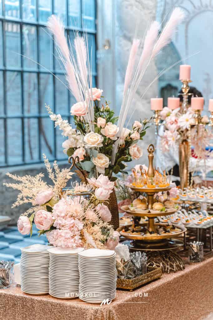 Elegant pink floral table centerpiece with dessert and appetizer display at Mongkol Catering event in Thailand.