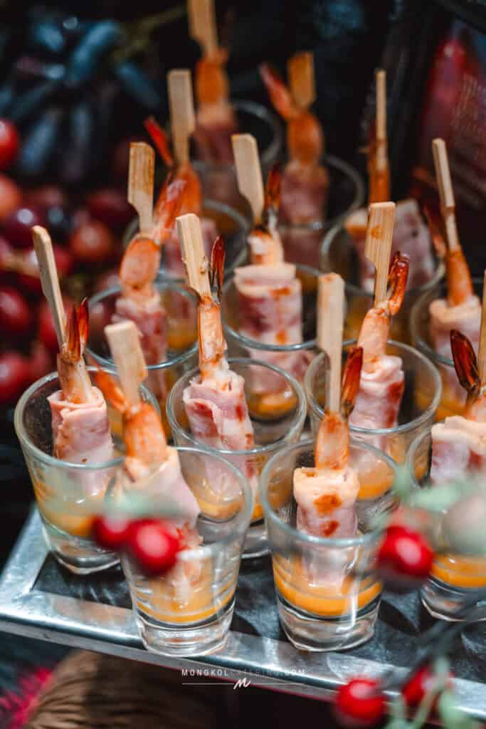 Succulent bacon-wrapped shrimp skewers served in shot glasses, perfect for Thai events and catering.